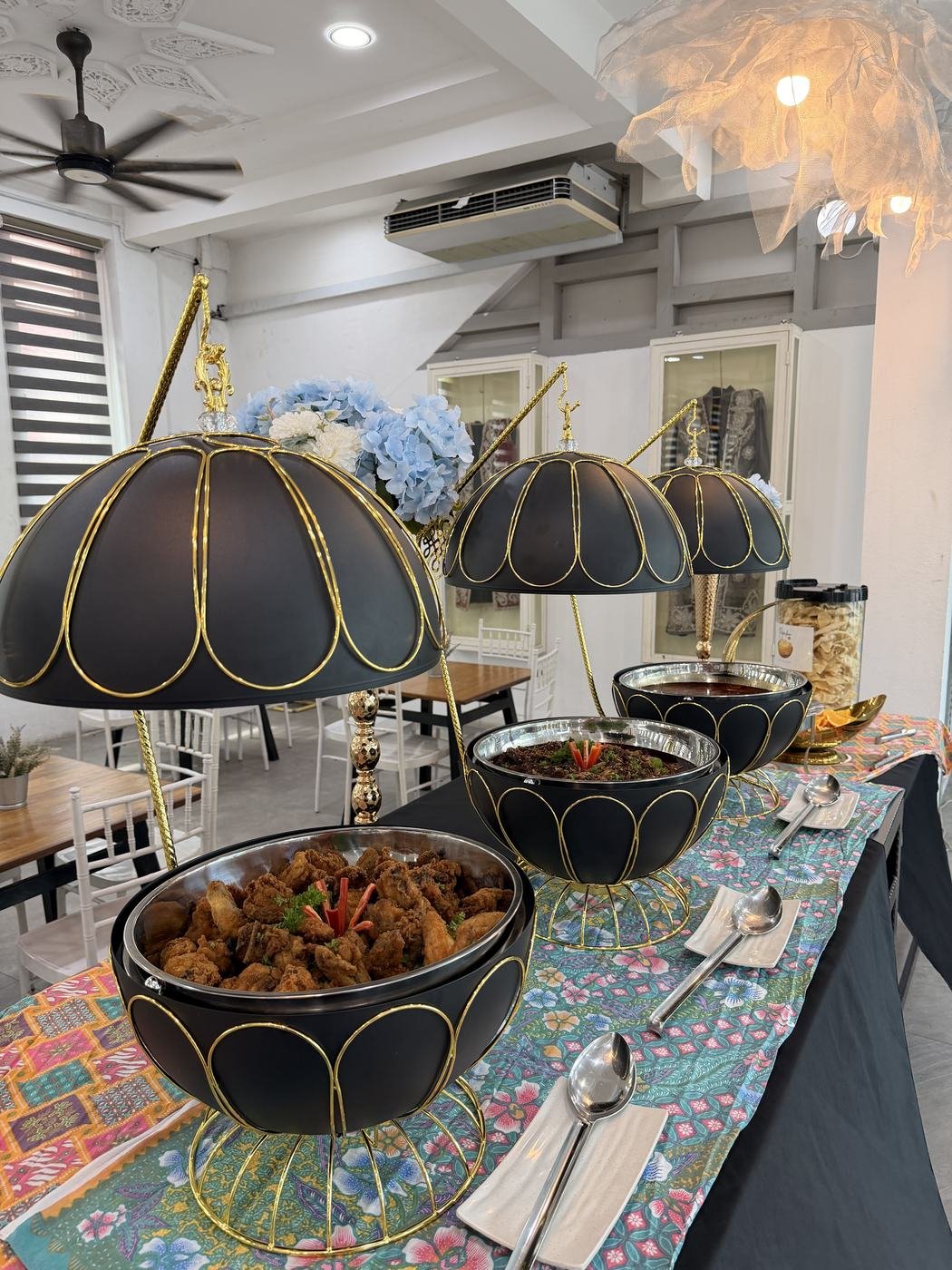 Hidangan rendang dan lauk dalam bekas saji hitam bercorak emas